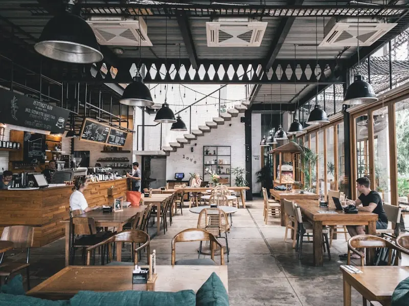 Sala de restaurante moderna com mesas de madeira e luz natural